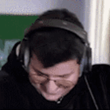 a man wearing headphones and glasses is smiling and looking down