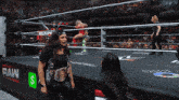 a woman in a black shirt stands in a wrestling ring with a sign that says raw on it