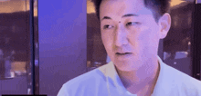 a man in a white shirt is standing in front of a blue wall .