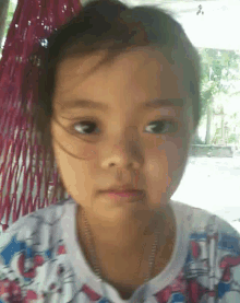 a little girl is sitting in a hammock and making a face