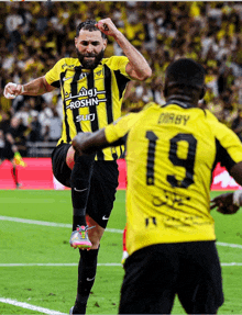a soccer player in a yellow and black jersey with the number 19 on the back