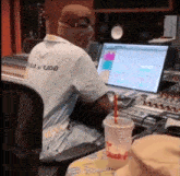 a man sitting in front of a computer with a dunkin donuts cup on the table