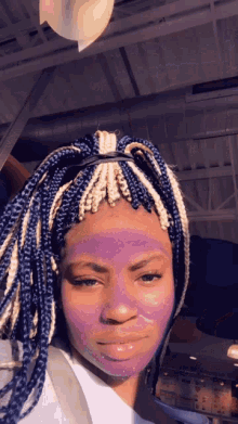 a woman with blue and white braids has a purple mask on her face