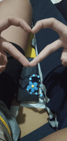 a person making a heart shape with their fingers next to a phone