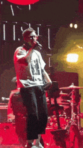 a man in a white shirt is singing into a microphone on stage