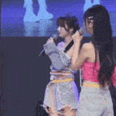 two girls are standing next to each other holding microphones .