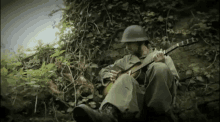a man in a helmet is playing a guitar while sitting in the woods .