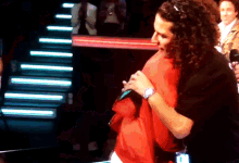 a man with long curly hair is hugging another man while holding a microphone