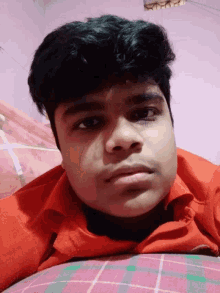 a close up of a young man 's face with a red shirt on