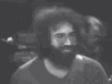 a man with a beard is smiling in a black and white photo .