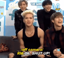 a group of young men are sitting on a couch and one of them is saying " off camera rm oh shut up "