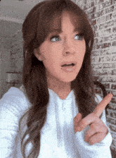 a woman with a surprised look on her face is pointing