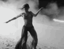 a woman in a bikini is dancing on a beach