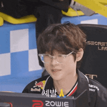a man wearing glasses and a red bull shirt sits in front of a computer