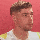 a young man with a beard is wearing a tie dye shirt and looking at the camera .