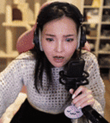a woman wearing headphones is holding a microphone in front of her .