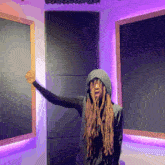 a person with dreadlocks is standing in front of a purple wall