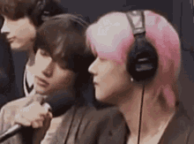 a woman with pink hair is wearing headphones and a microphone .