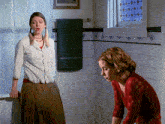two women standing in a bathroom with a green towel on the wall