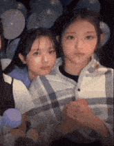 two girls are standing next to each other with balloons behind them
