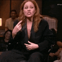 a woman with red hair is sitting in a chair and making a funny face .