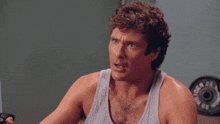 a man wearing a tank top is lifting a dumbbell in front of a gold's gym weight