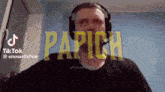 a man wearing headphones is standing in front of a screen that says papich .