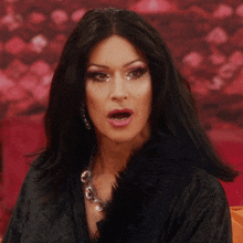 a woman with long black hair is wearing a black fur coat and a necklace