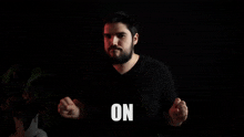 a man with a beard holds up his hands in front of the word braaa