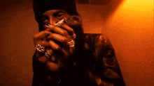 a person with rings on their fingers is holding a cigarette in front of their face