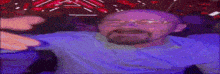 a man with glasses and a beard is laying on a bed in a purple room .