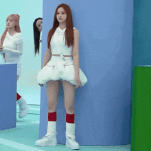 a woman in a white dress and red socks is standing in front of a blue wall