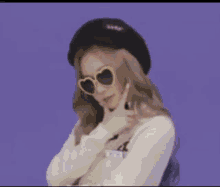 a woman wearing sunglasses and a hat is standing in front of a smiley face .