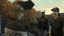 a man with a mustache is talking to a woman in front of a sign that says traveler motel