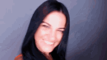 a woman with black hair is smiling and making a funny face .