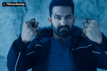 a man with a beard is holding a pair of knuckle dusters in his hands