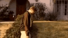 a man is standing in front of a house with a christmas tree .