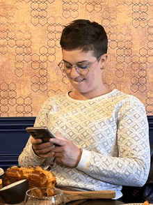 a woman is sitting at a table looking at her cell phone