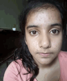 a close up of a girl 's face with a pink shirt on