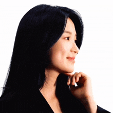 a woman with long black hair is smiling with her hand on her face