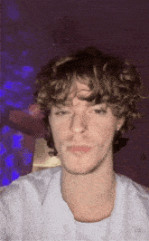 a young man with curly hair is wearing a nose ring