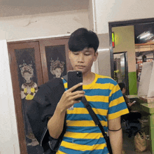 a man in a blue and yellow striped shirt is taking a picture of himself