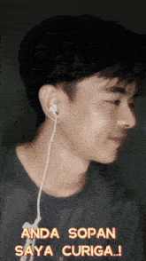 a young man wearing ear buds with the words anda sopan saya curiga on the bottom