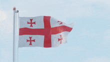 a flag with a red cross on it is flying in the wind