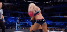 two women are wrestling in a wrestling ring with a referee watching