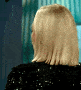 a woman with blonde hair is wearing a black sequined shirt