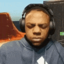 a man wearing headphones and a black hoodie is making a funny face .