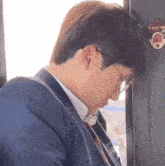 a man in a suit and tie is sitting on a bus with his head on the door .