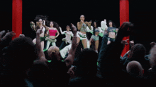 a group of women are dancing in front of a crowd of people