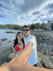 a man and a woman are posing for a picture on a beach